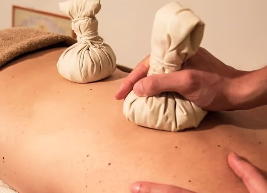 Ayurvedische Behandlung mit warmen Kräuterstempeln